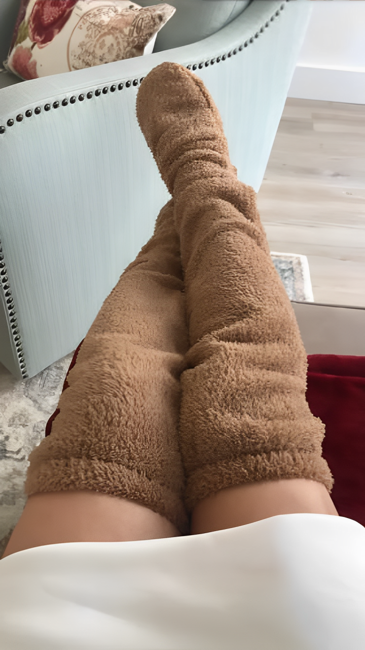 A woman lying down and wearing brown plush knee high socks.