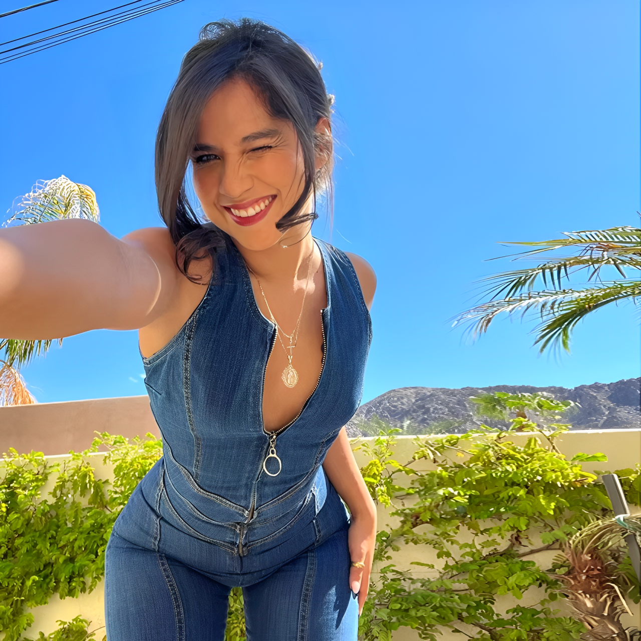 A woman wearing a blue backless heart denim jumpsuit.